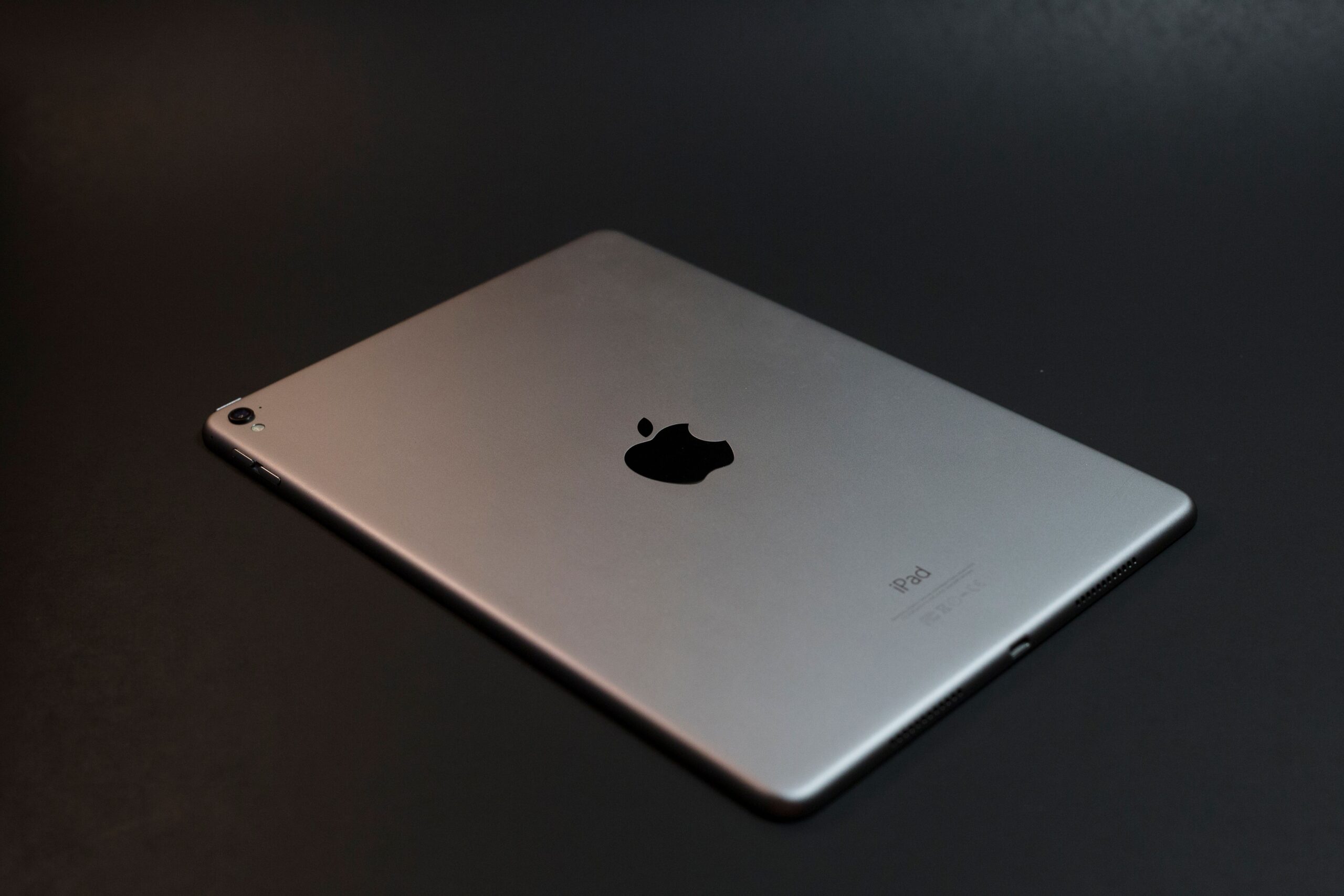 A modern silver tablet with a sleek design on a dark surface, showcasing advanced technology.